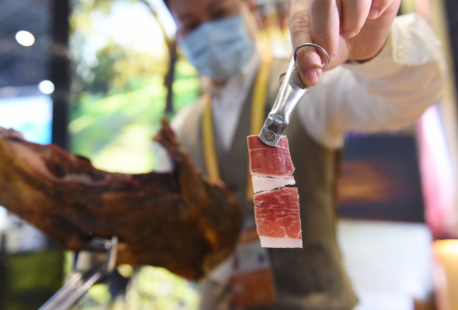 An exhibitor shows a slice of ham from Spain at the Food and Agricultural Products exhibition area during the third China International Import Expo (CIIE) in Shanghai, east China, Nov. 7, 2020. (Xinhua/Zhao Dingzhe) XxjhmeE007098 20210521 CBMFN0A003